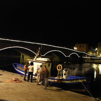 Beleuchtete Brücke in Bosa mit Fischerboot